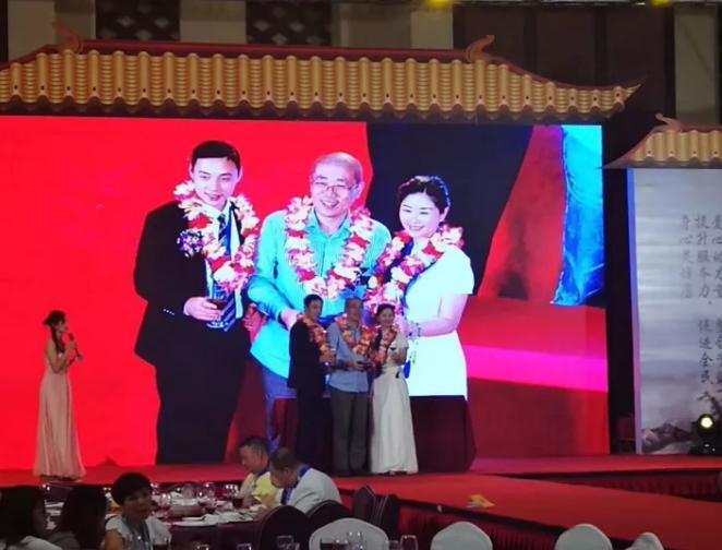 奧科維董事長許練（中）在拍賣活動中成功拍下手鏈，上臺接受花環(huán)饋贈